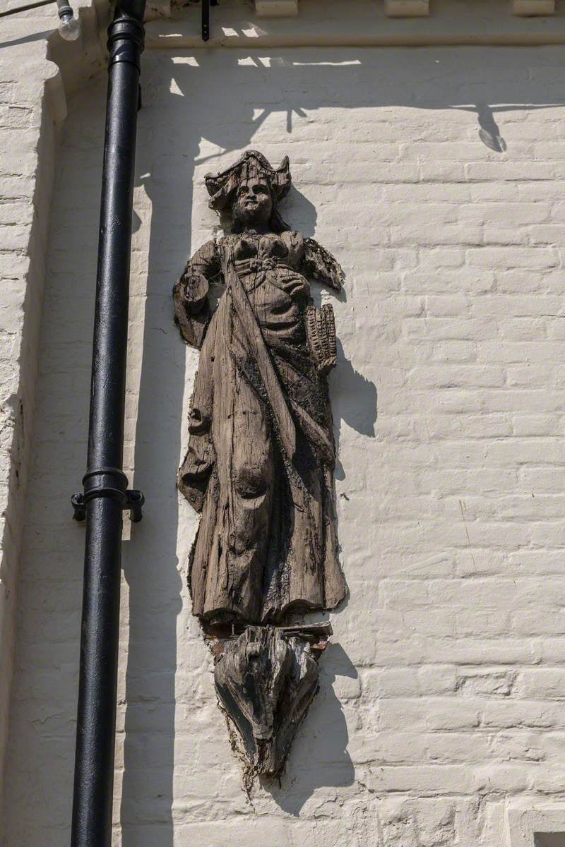 A wooden carving of female pirate Mary Read mounted on the wall of a tavern